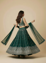 Load image into Gallery viewer, Woman wearing a green and silver traditional outfit on a beige background