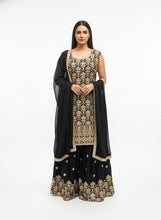 Load image into Gallery viewer, Woman wearing a black and gold traditional outfit in a room with yellow doors and patterned rug.
