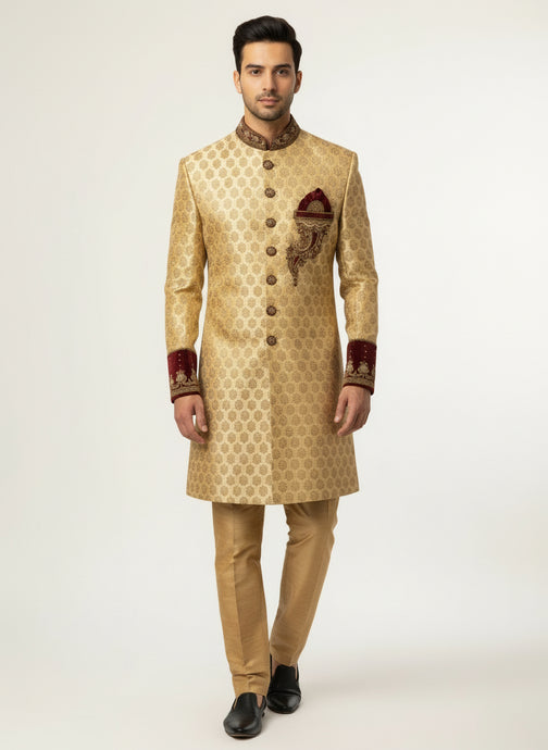 Man wearing a traditional gold sherwani with intricate patterns on a white background
