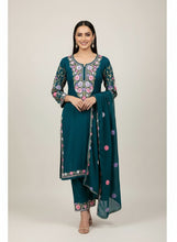 Load image into Gallery viewer, Teal traditional outfit with floral embroidery on a rack against a yellow wall.
