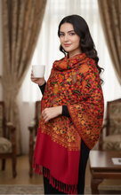 Load image into Gallery viewer, Woman wearing a red and orange patterned shawl in an elegant room.
