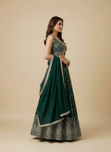 Load image into Gallery viewer, Woman wearing a green and silver traditional outfit on a beige background
